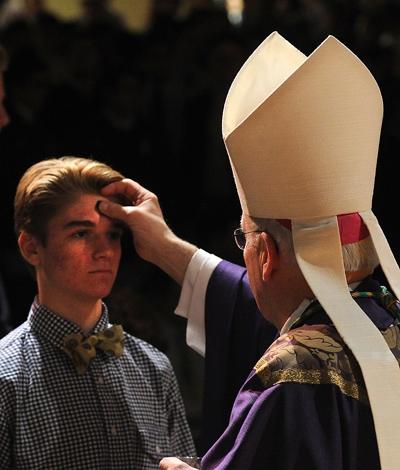 Bishop Richard J. Malone gives ashes to Canisius High School senior Brahm Brooks during Ash Wednesday Mass in the school gym. (Dan Cappellazzo/Staff Photographer)